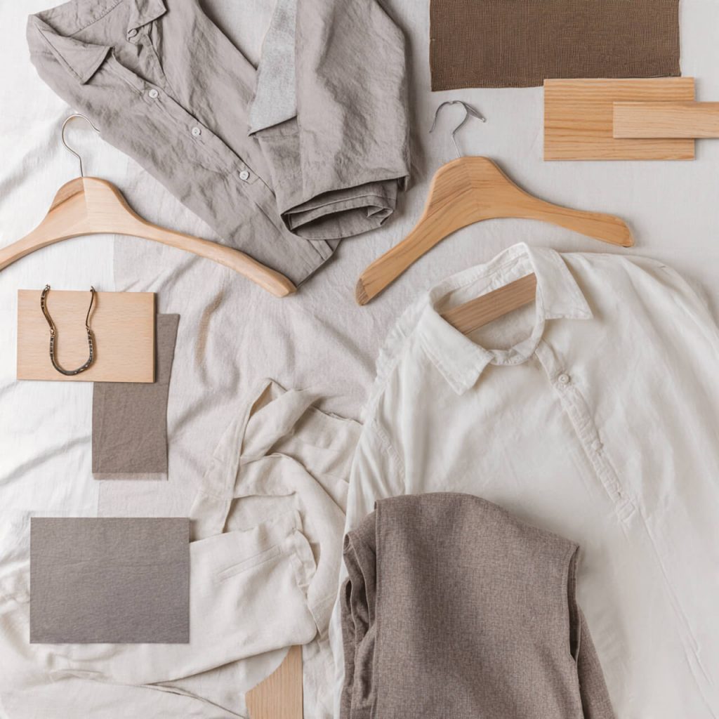 Flatlay of organic cotton clothing and ethical fashion accessories in soft neutral tones