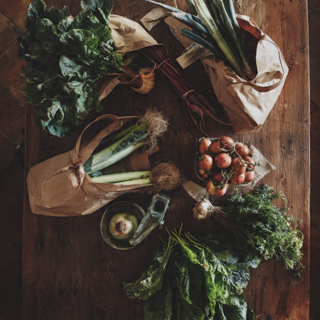 Flatlay of fresh artisan produce and market goods arranged on rustic wooden textures